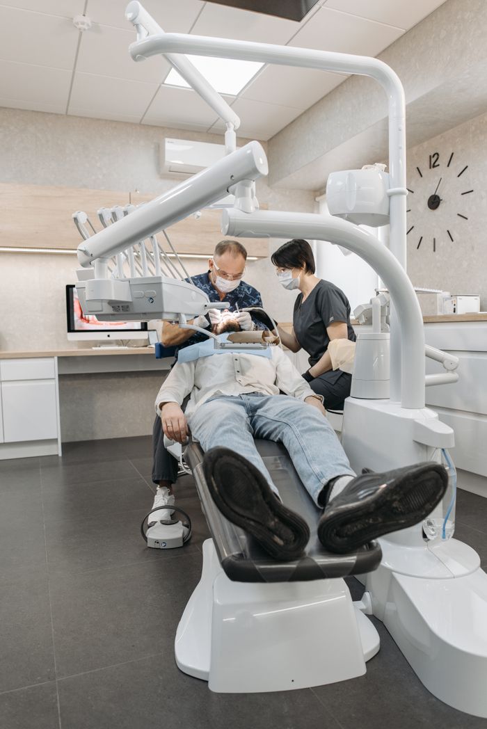 A dentist and assistant examine a patient at a modern dental clinic.